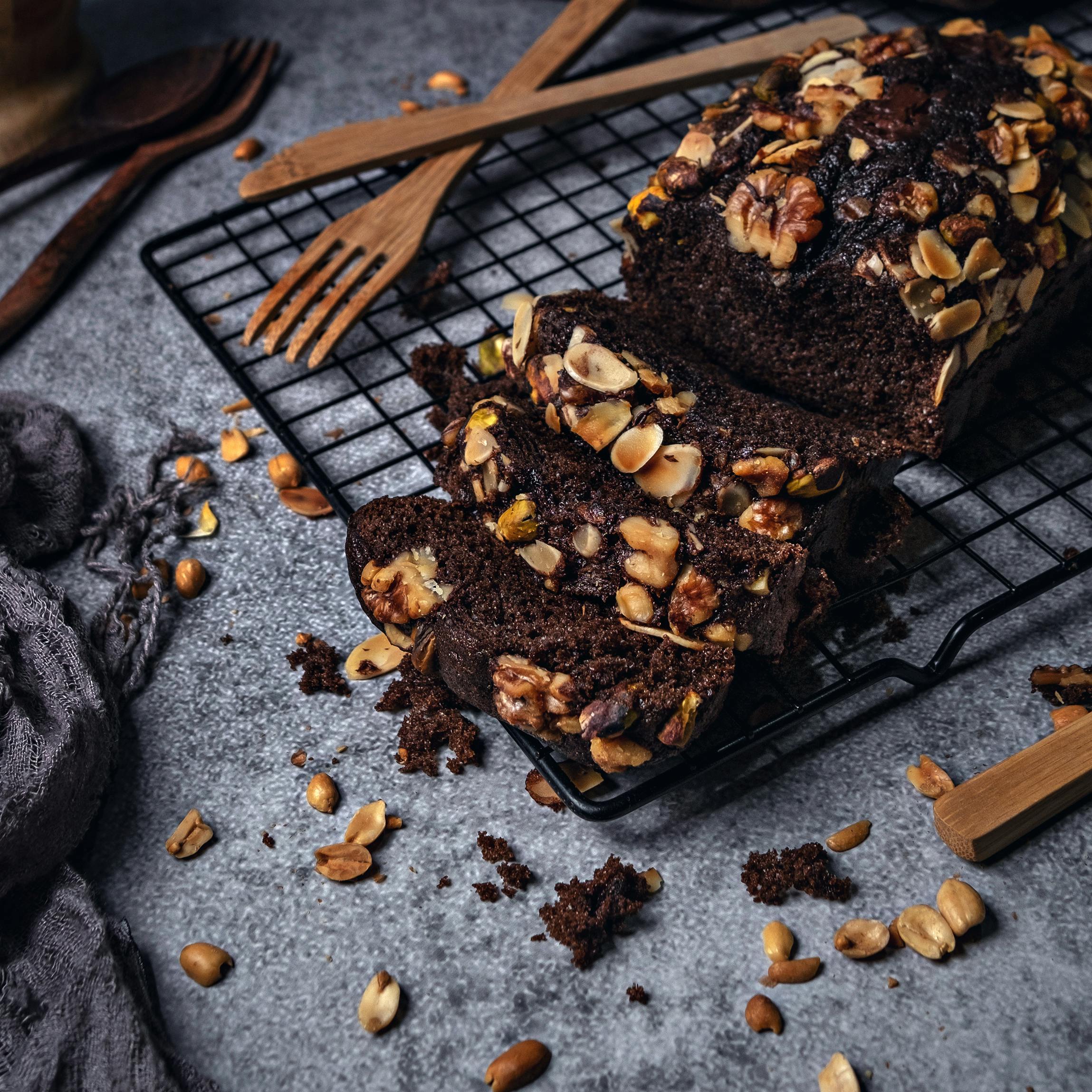 Rich chocolate cake topped with nuts on a cooling rack, perfect for desserts.